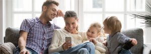 Family sitting on a couch smiling while looking at the mother's phone